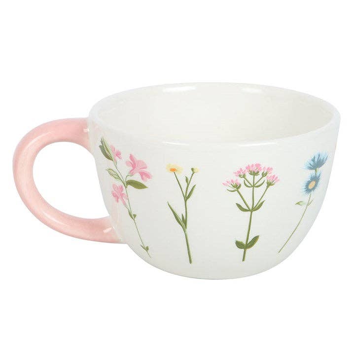 White ceramic mug with a floral pattern and a pink handle.