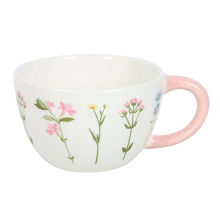 White ceramic mug with a floral pattern and a pink handle.