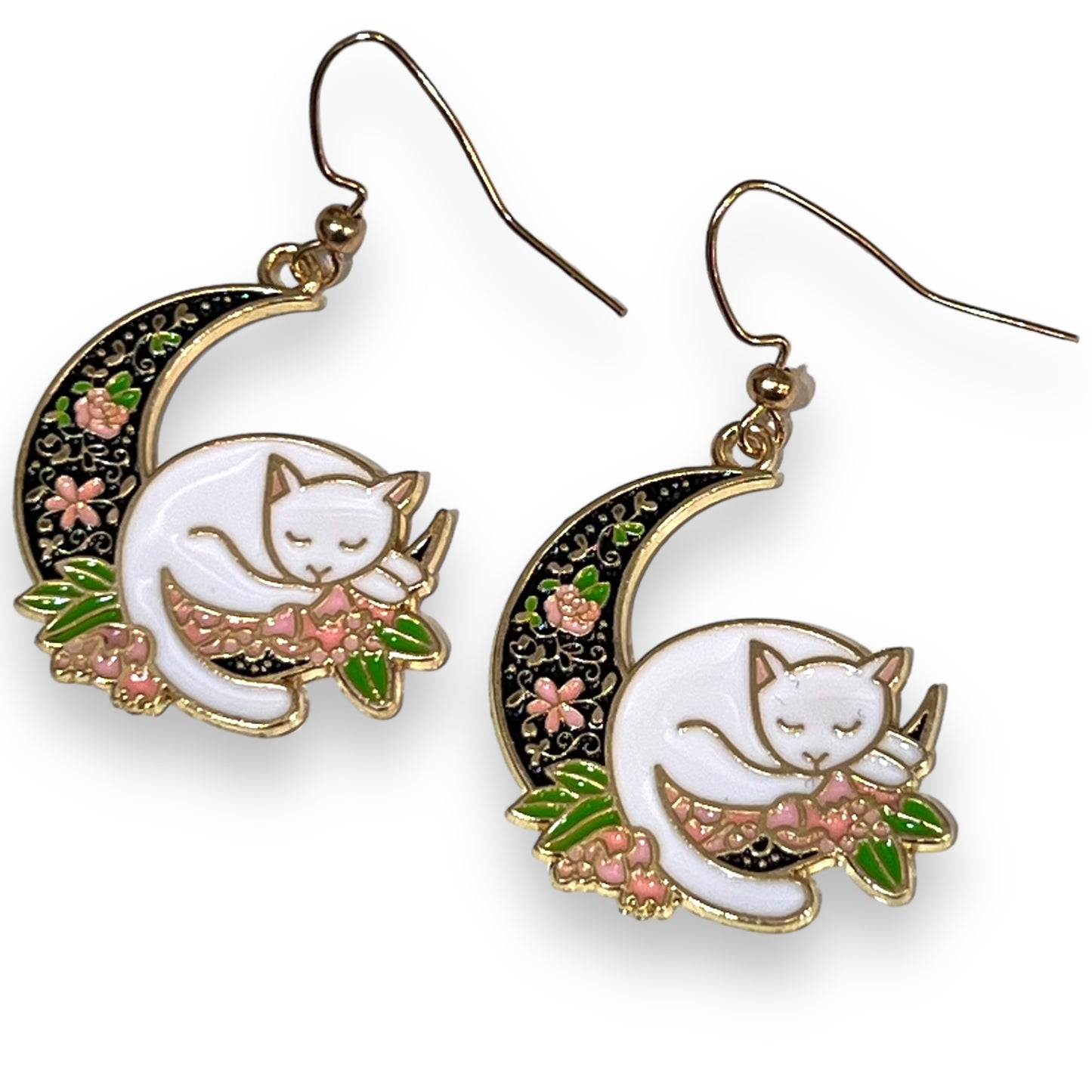 A pair of earrings of a white cat sleeping on a crescent moon surrounded by flowers.