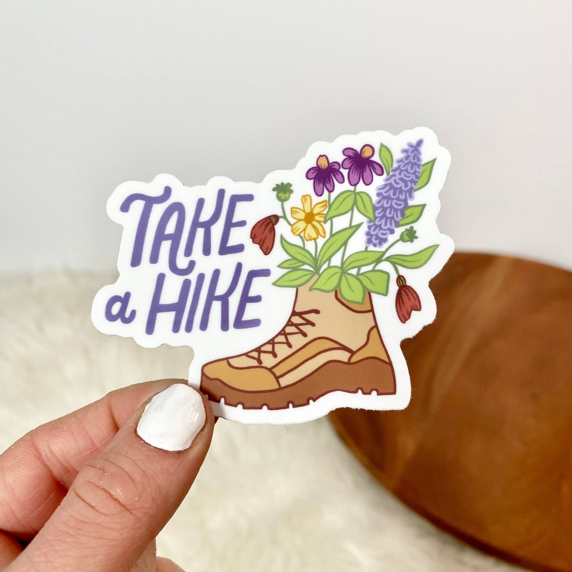 Sticker with flowers sticking out of a boot and the phrase "Take a Hike"
