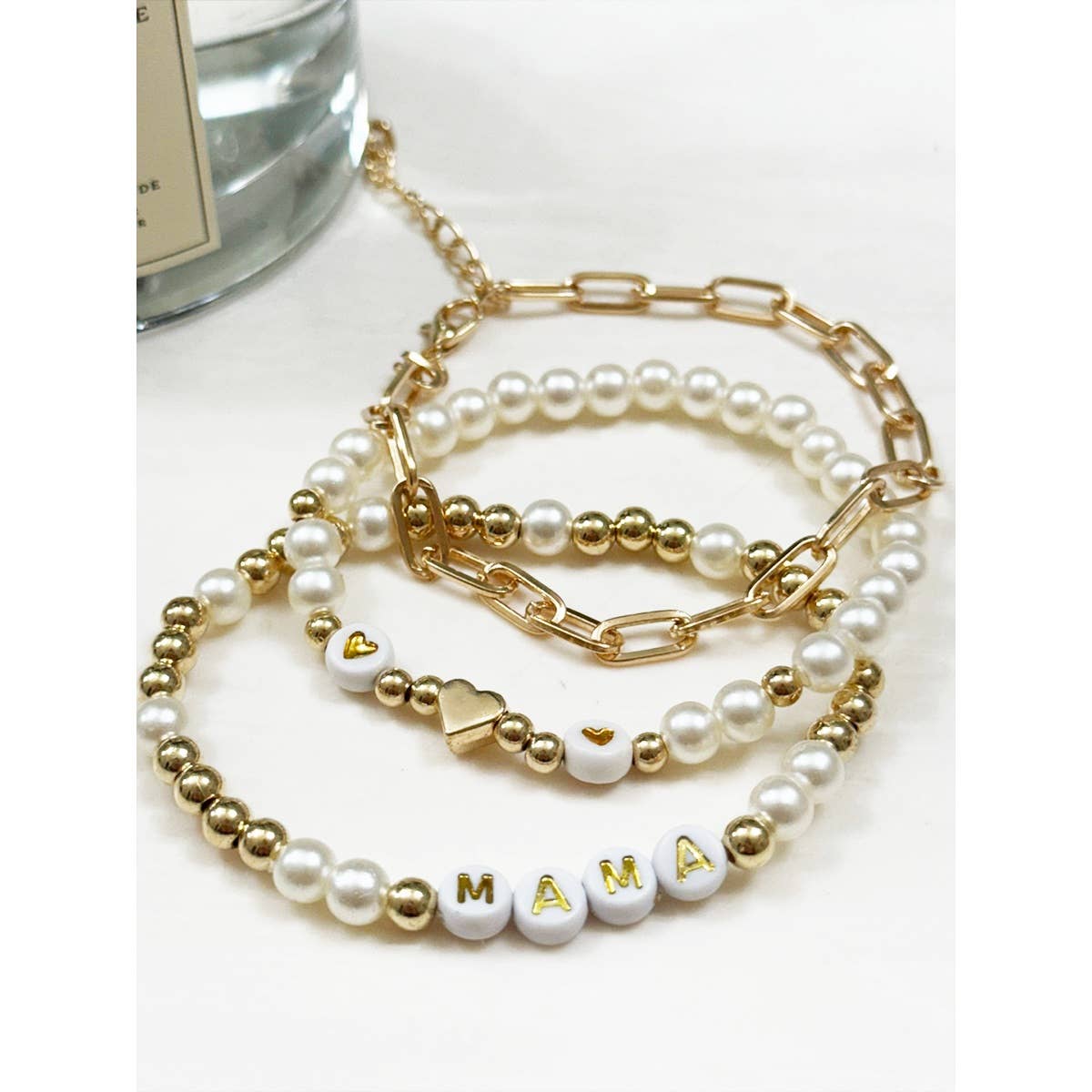 Closeup of a set of beaded and chain bracelets featuring the beads that spell "MAMA".