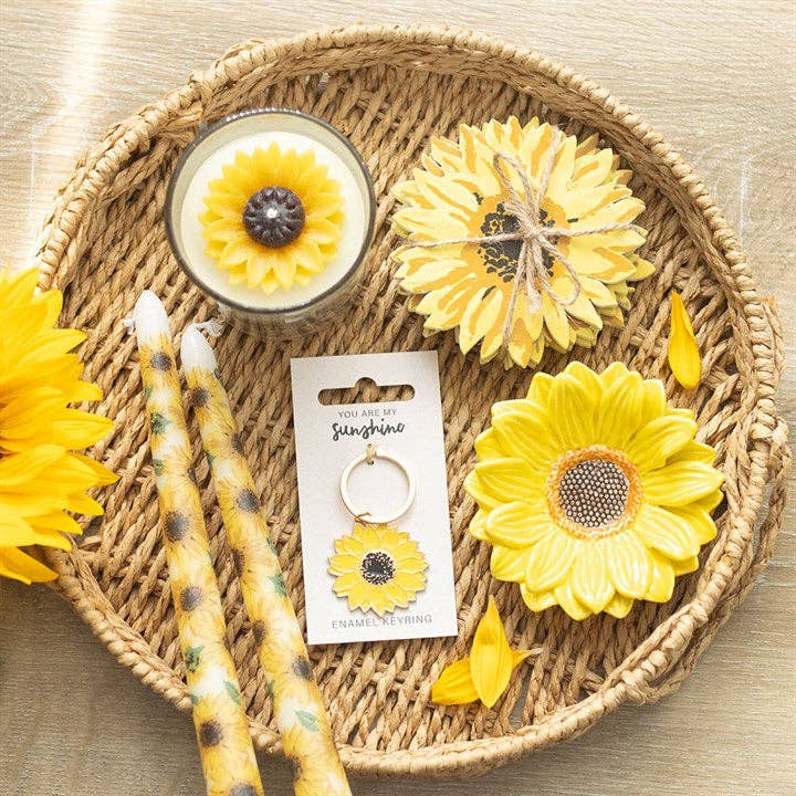 A collection of sunflower items, including a keychain, candles, coasters, and ring dish. Pictured for size reference and aesthetic.