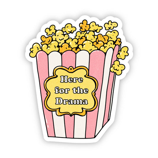 This sticker shows a classic popcorn bucket with pink and white stripes, overflowing with popcorn, and the sentiment "Here for the Drama".