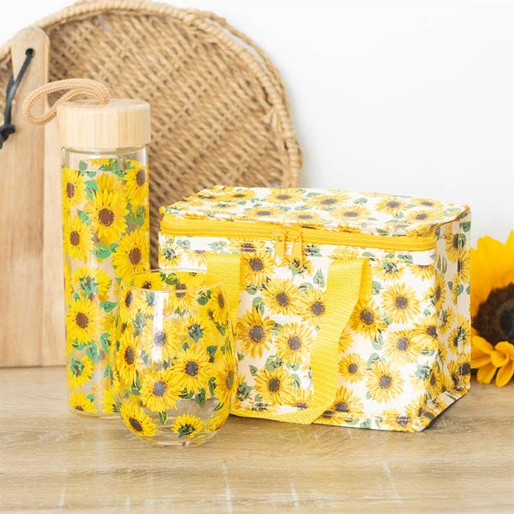 A collection of items with an all-over sunflower pattern, including a stemless wine glass, water bottle, and lunch bag. Pictured for size reference.