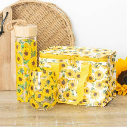 A collection of items with an all-over sunflower pattern, including a stemless wine glass, water bottle, and lunch bag. Pictured for size reference.